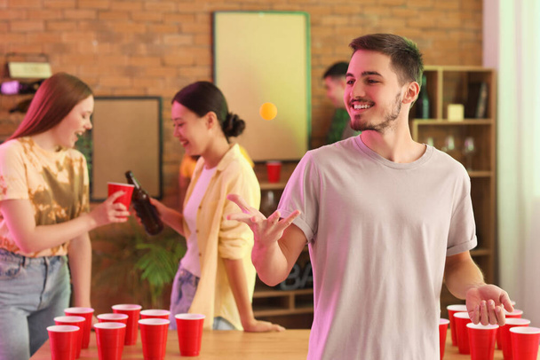 パーティーでビールポンのためのボールを持つ若い男 - 写真・画像