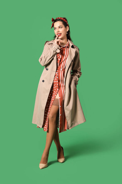Portrét krásné pin-up žena v kabátě na zeleném pozadí - Fotografie, Obrázek