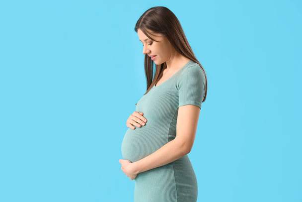 Mulher grávida bonita no fundo azul
 - Foto, Imagem
