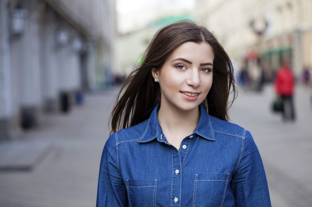 Portrait of a beautiful young woman in a blue jeans shirt on the - 写真・画像