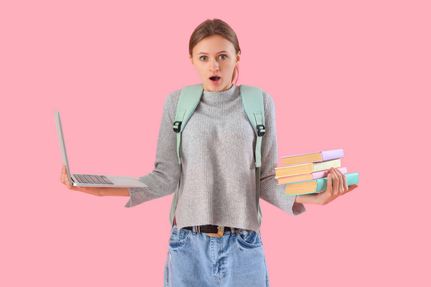 Estudante surpreendida com livros e laptop sobre fundo rosa. Fim do conceito de escola - Foto, Imagem
