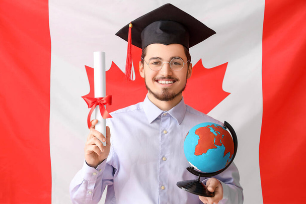 Άνδρας μεταπτυχιακός φοιτητής με δίπλωμα και υδρόγειο σε φόντο σημαία Καναδά - Φωτογραφία, εικόνα