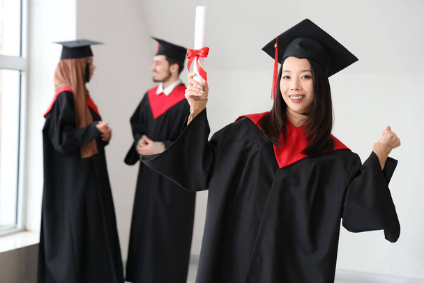 Asiática estudiante graduada con diploma celebrando el éxito en sala de luz - Foto, imagen