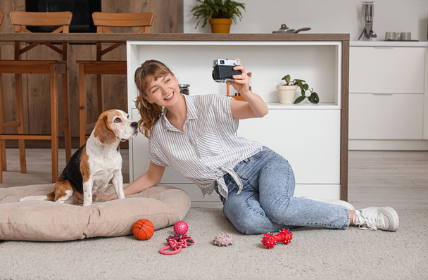 Fiatal nő csinál szelfi aranyos beagle kutya és játékok otthon - Fotó, kép