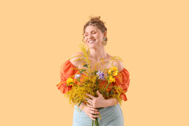 Happy young woman with bouquet of beautiful flowers on yellow background - 写真・画像