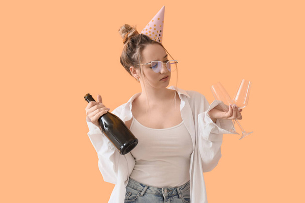 Young businesswoman with hangover and champagne after Birthday party on beige background - Photo, image