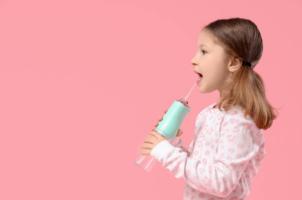 Linda niña con riego oral sobre fondo rosa - Foto, imagen