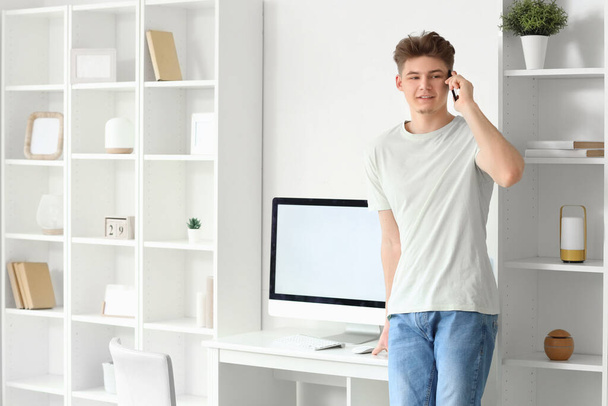 Nuori mies puhuu matkapuhelimella kotona - Valokuva, kuva