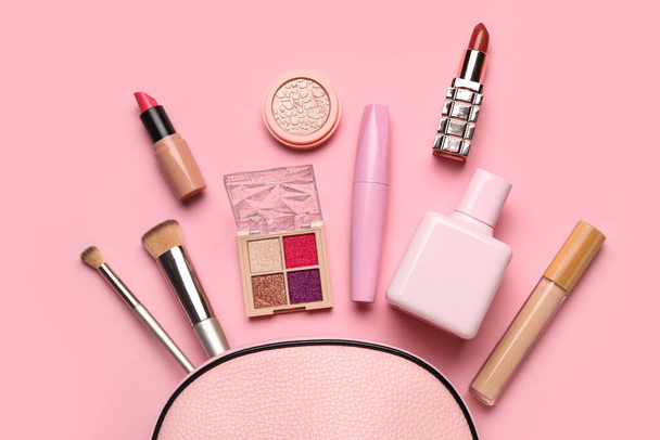 ピンクの背景にバッグが付いている装飾的な化粧品のセット. トップビュー - 写真・画像