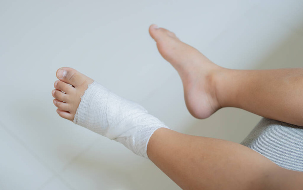 Draufsicht auf bandagierte Füße eines Kindes aufgrund eines kleinen Unfalls nach einem Sturz. Erste Hilfe für Kinder nach Verletzungen / Traumata - Foto, Bild