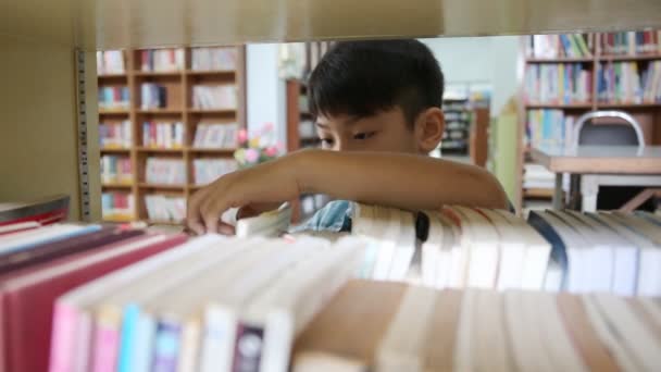 Malý asijský student čte knihu v knihovně . - Záběry, video