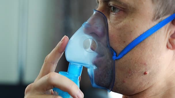 Evde nebulizör maskesi takan sağlıksız bir adam nefes alıyor. Sağlık, tıbbi ekipman ve insan konsepti. Yüksek kalite 4k görüntü - Video, Çekim