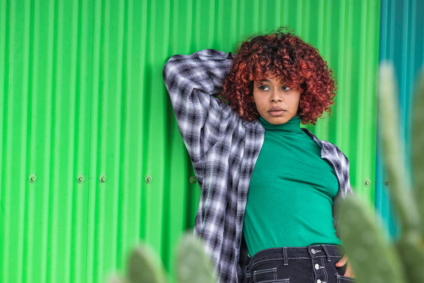 ストリートの緑の壁に傾いているカジュアルなスタイルの少女 - 写真・画像