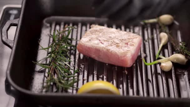 tonijnsteak gebakken in olie in een koekenpan met rozemarijn en knoflook. concept van een visrestaurant - Video