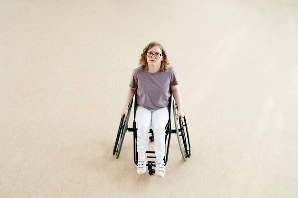 Θέα υψηλής γωνίας μακρινή βολή νεαρής καυκάσιας χορεύτριας αναπηρικής πολυθρόνας με αναπηρία στο ευρύχωρο δωμάτιο - Φωτογραφία, εικόνα