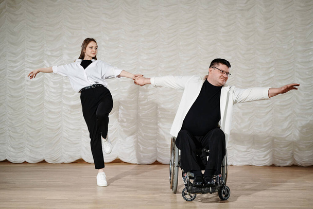 Long shot of young woman and mature man with disability in wheelchair performing dance on stage, copy space - Photo, Image