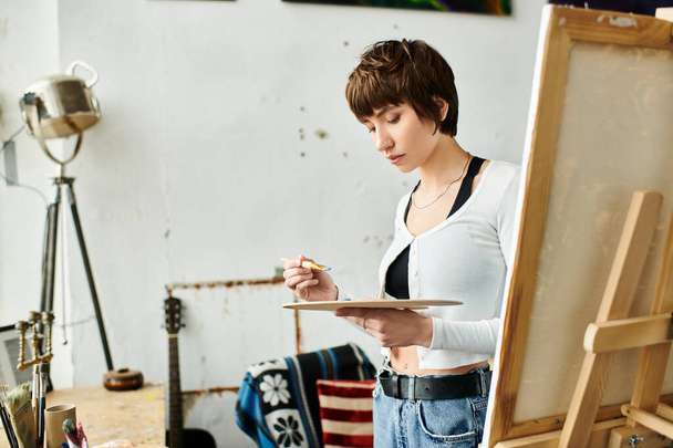 Kobieta maluje na sztaludze w studiu. - Zdjęcie, obraz