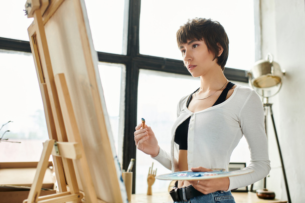 Woman with easel and paintbrush, embracing creativity. - Photo, Image