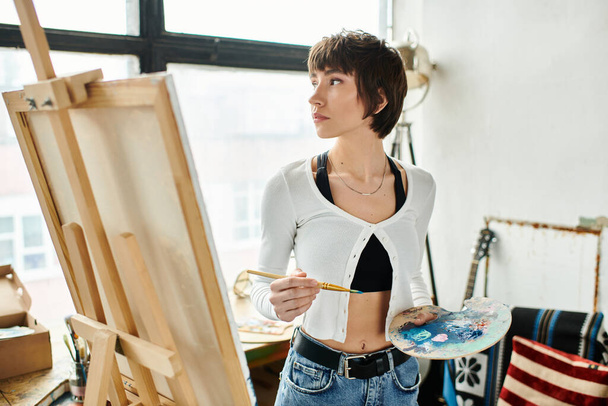 Una mujer sosteniendo un pincel y una paleta. - Foto, Imagen
