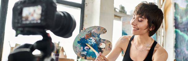 A woman in a black tank top creatively holds a paintbrush. - Photo, Image