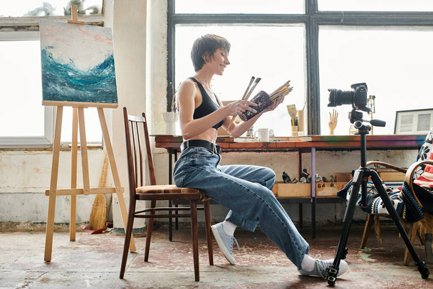 Pretty woman sitting in chair, showing how to paint on camera. - Photo, Image