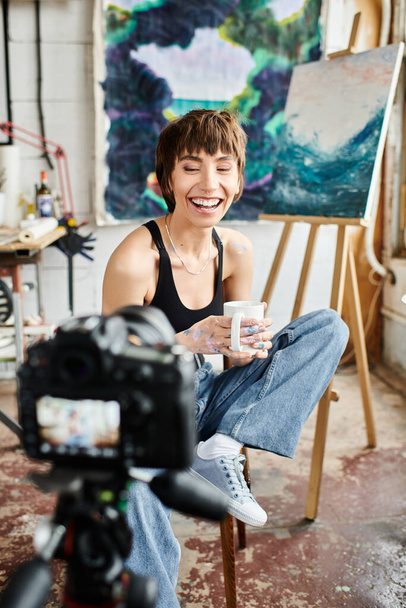 Μια κομψή γυναίκα ποζάρει με μια κάμερα σε ένα ζωντανό σκηνικό στούντιο. - Φωτογραφία, εικόνα