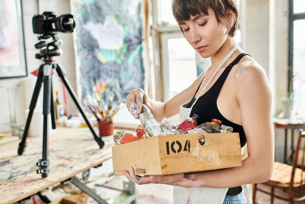 Женщина с коробкой, заполненной различными красками. - Фото, изображение