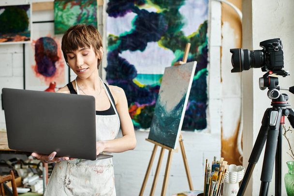 Bir kadın bir tablonun önünde dizüstü bilgisayar tutuyor.. - Fotoğraf, Görsel