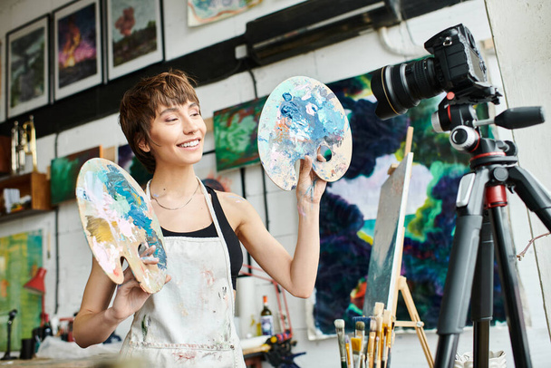 Une femme tient gracieusement deux palettes devant une caméra. - Photo, image