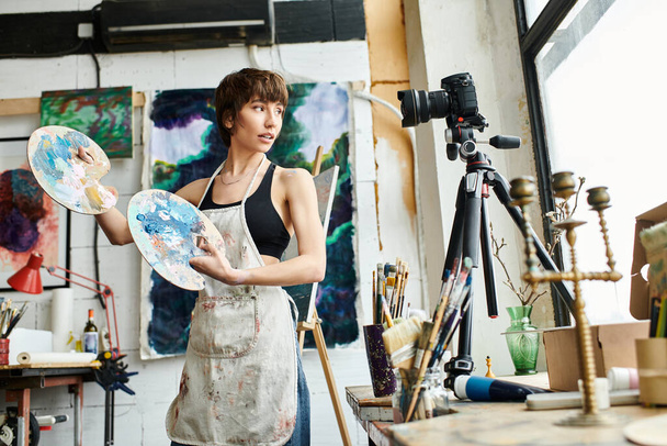 Dengeli bir kadın iyi aydınlatılmış bir stüdyo ortamında paletleri dikkatle tutar.. - Fotoğraf, Görsel