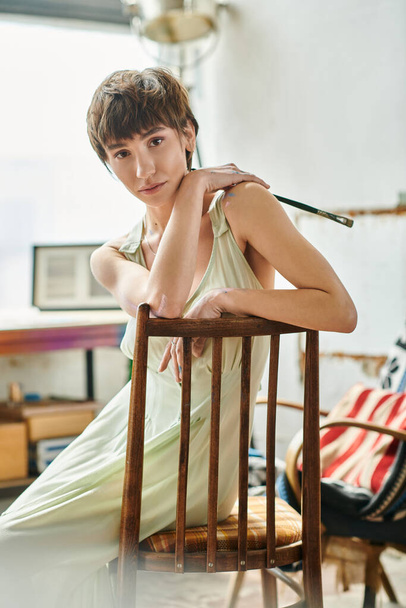 Uma mulher se senta elegantemente em cima de uma cadeira de madeira. - Foto, Imagem