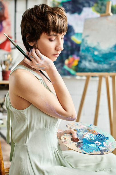 Une femme assise, tenant un pinceau. - Photo, image