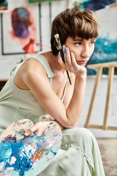 A woman in stylish attire sits in art studio. - Photo, Image