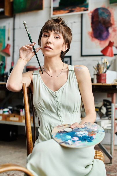 A woman creates magic with a paintbrush while seated in a chair. - Photo, Image
