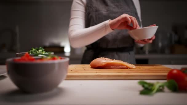Άποψη της νεαρής γυναίκας να καρυκεύει φιλέτο σολομού στη σύγχρονη κουζίνα της, ετοιμάζοντας ένα υγιεινό φαγητό. Μαγειρική έννοια - Πλάνα, βίντεο