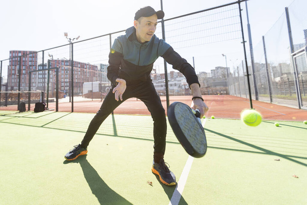 Um homem a jogar ténis de remo. Saltar e atirar a bola. Foto de alta qualidade - Foto, Imagem