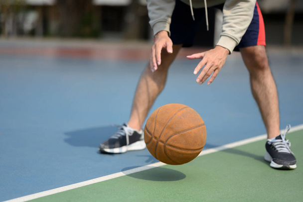 Tiro cortado de homem desportivo saltando bola em uma quadra urbana. Esporte e conceito de estilo de vida ativo. - Foto, Imagem