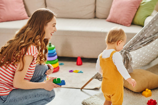 Egy fiatal anya örömmel vesz részt a kislányával egy vidám játékban egy hangulatos nappaliban.. - Fotó, kép