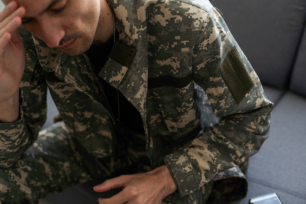 Soldat déprimé avec bouteille assise dans le salon. L'alcoolisme. Photo de haute qualité - Photo, image
