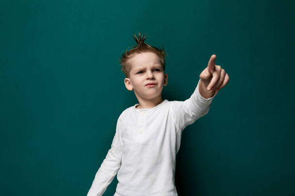 A young boy standing outdoors, pointing at an unseen object in the distance with his index finger. He seems curious and engaged in what he is pointing at. - Photo, Image