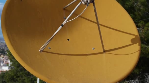 Schwenken Sie von oben nach unten, von einer alten orangefarbenen Satellitenschüssel hinunter zu einer altmodischen Radio- oder Fernsehantenne. Die Satellitenantenne wurde bereits neu gestrichen. - Filmmaterial, Video