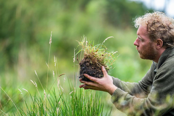 australischer Bodenwissenschaftler. Regenerativer Biobauer, der Bodenproben entnimmt und sich das Pflanzenwachstum auf einem Bauernhof ansieht. Nachhaltigkeit praktizieren  - Foto, Bild