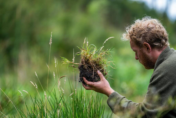 Der Student der Bodenwissenschaft Landwirtschaft betrachtet eine Bodenprobe. Mädchen auf einem Bauernhof mit Blick auf Pflanzenwurzeln in Australien - Foto, Bild