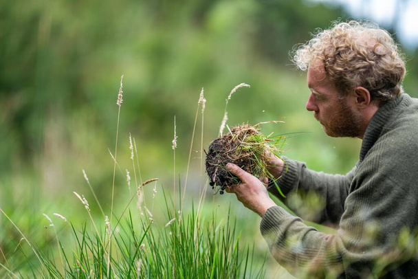 Landwirt hält Erde in der Hand und tastet Kompost auf einem Feld in Tasmanien Australien. bodenwissenschaftler in australien - Foto, Bild