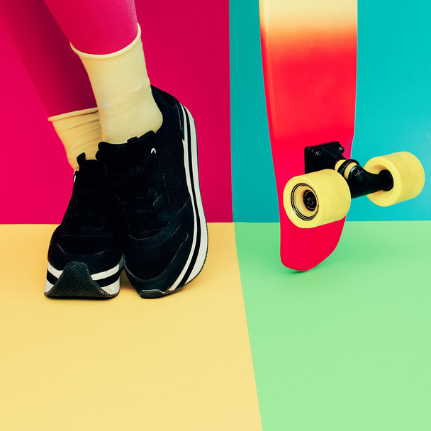 Ноги модели с скейтбордом на ярком эксклюзивном бэкграунде
 - Фото, изображение