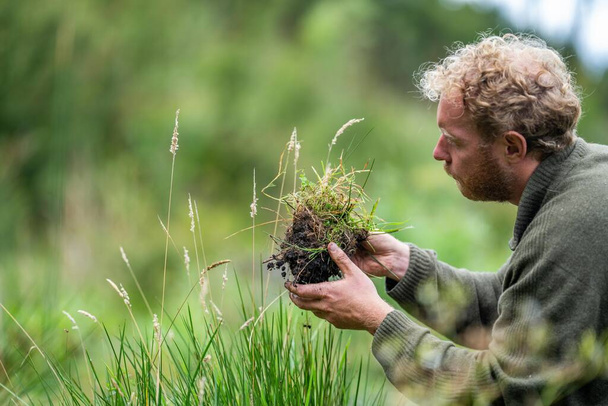 australischer Bodenwissenschaftler. Regenerativer Biobauer, der Bodenproben entnimmt und sich das Pflanzenwachstum auf einem Bauernhof ansieht. Nachhaltigkeit praktizieren  - Foto, Bild