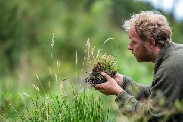 Landwirt sammelt Bodenproben in einem Reagenzglas auf einem Feld. Agronom überprüft Kohlenstoff im Boden und Pflanzengesundheit - Foto, Bild