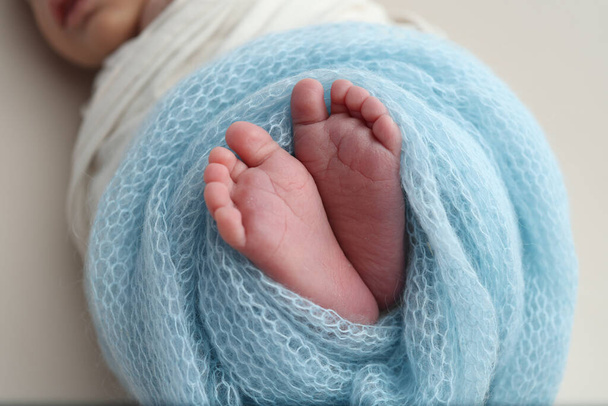 The tiny foot of a newborn baby. Soft feet of a new born in a blue wool blanket. Close up of toes, heels and feet of a newborn. Macro photography.  - Photo, Image