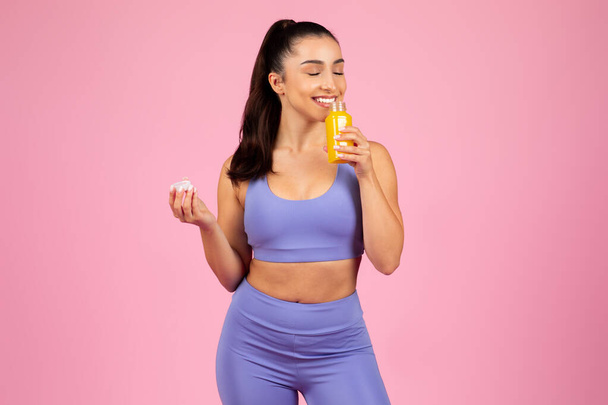 Una mujer en ropa deportiva decidiendo entre una píldora vitamínica y jugo de naranja natural - Foto, Imagen