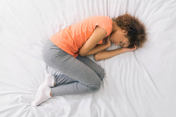Afrikai-amerikai nő alszik, göndör fel az ágyban, felülnézet - Fotó, kép